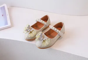 Detalle de zapatos Mary Jane dorados con lentejuelas, lazo de malla y perlas