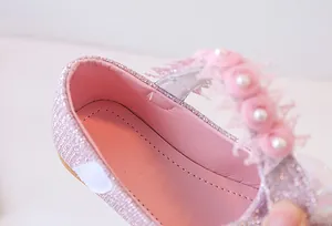 Detail of pink sparkly girls shoes with lace flowers and white pearl embellishments