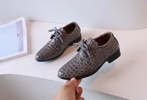 Detailed close-up of boys' oxford dress shoes with grey embossed crocodile texture