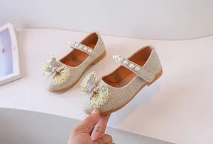 Detalle de zapatos Mary Jane dorados para niña con purpurina, lazo y perlas blancas
