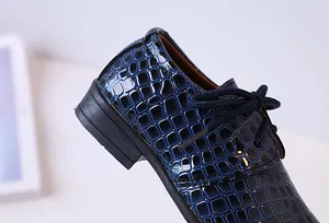 Détail gros plan de chaussures habillées bleu foncé pour garçons en cuir gaufré crocodile