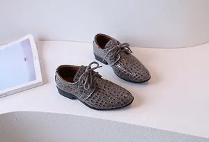 Close-up of boys' grey crocodile embossed oxford dress shoes with lace-up detail