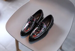 Détail des mocassins en cuir verni noir pour garçons avec texture rouge et boucle en métal