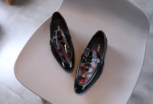 Gros plan de mocassins garçon en cuir verni noir avec motif léopard rouge et boucle en métal