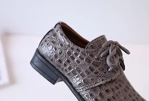 Detailed macro view of dark grey crocodile embossed leather on lace-up formal boys shoes