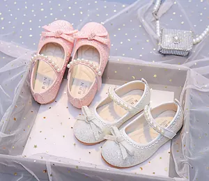 Detailed close-up of girls' glitter Mary Jane shoes with bow and pearl straps in gift box