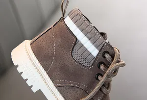 Detail von Kinderstiefeln aus braunem Wildleder mit Strickkragen und dicker weißer Sohle