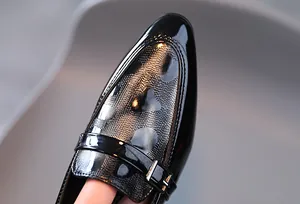 Gros plan de mocassins en cuir noir pour garçons avec pois argentés et boucle métallique