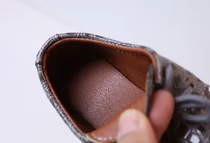 Detail view of boys' leather shoes showing textured brown lining and grey embossed finish