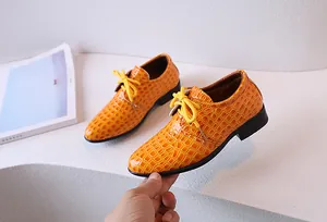 Détail de la chaussure pour garçon en cuir verni orange avec texture croco et semelle souple
