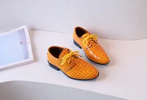 Détail d'une chaussure pour garçon en cuir orange à motif crocodile avec lacets et semelle