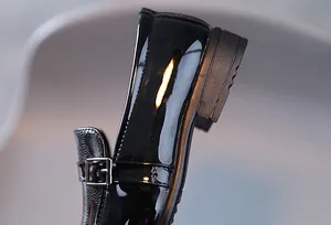 Détail macro de chaussures en cuir verni noir pour garçons avec boucle argentée