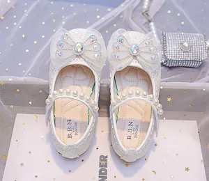 Détail de chaussures de princesse à paillettes blanches avec nœud et bride en perles