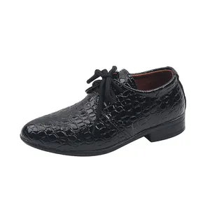 Close-up of black boys' leather dress shoes featuring embossed crocodile texture and laces