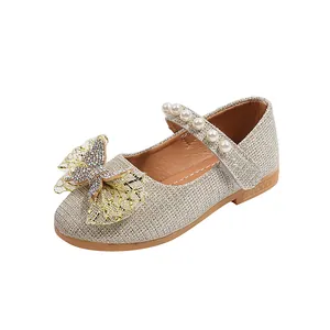 Detalle de zapatos de princesa dorados para niña con lazo brillante y correa de perlas