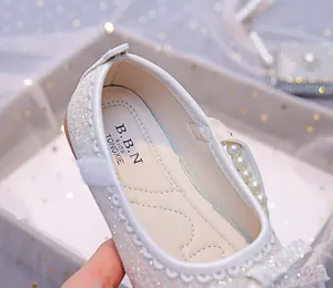 Detailed macro view of silver glitter girls princess shoes with pearls and bow decoration