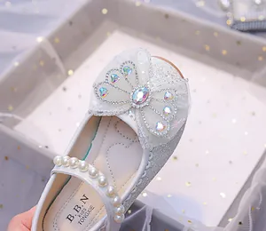 Détail de chaussures pailletées pour filles avec nœud en résille et perles nacrées