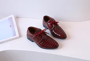 Gros plan de chaussures Oxford bordeaux pour garçon avec texture crocodile et lacets