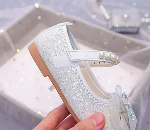 Détail de chaussure Mary Jane blanche à paillettes avec perles et nœud en strass
