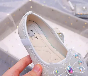 Détail de chaussures argentées pailletées pour filles avec nœud en strass et bride perle
