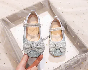 Dettaglio delle ballerine Mary Jane glitterate con grande fiocco di strass e perle