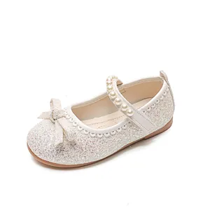 Sparkly white Mary Jane shoes for girls with pearl strap and bow detail on a clean white background