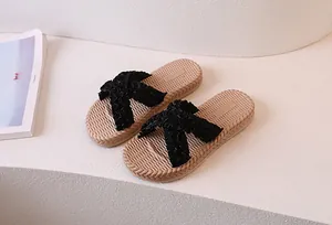 Detail of black pleated cross straps and anti-slip straw texture sole on summer slides