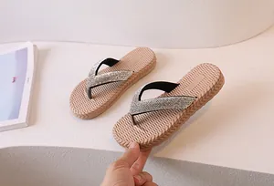 Close-up of beige flip-flops featuring black straps embellished with sparkling silver rhinestones
