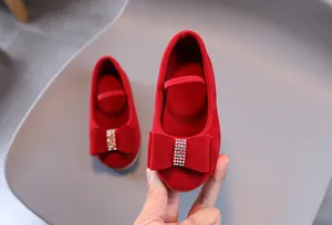 Détail de chaussures de princesse en daim rouge pour filles avec nœud en strass