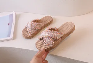 Dettaglio dei cinturini in ecopelliccia glitterata e plantare intrecciato di sandali