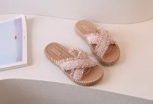 Dettaglio di sandali piatti beige con fasce incrociate in tweed e suola interna intrecciata