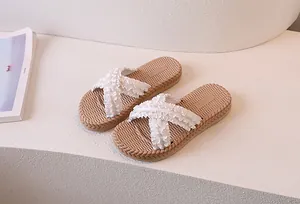 Detail view of white ruffled cross-straps and woven texture footbed of flat slide sandals