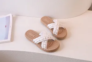 Close-up of beige slide sandals featuring elegant ruffled cross straps and woven texture sole