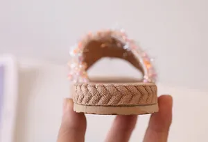 Dettaglio di sandalo con zeppa decorato con fiori di perline e bordo suola intrecciato