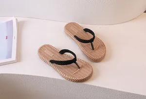 Detail of woven flip-flops with faux grass texture and black straps on white stairs