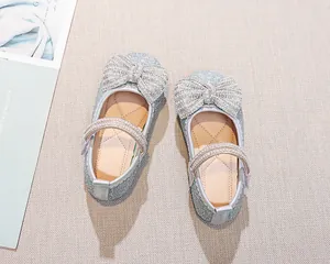 Vista dall'alto di scarpe argentate da ragazza con fiocco di strass e cinturino Mary Jane