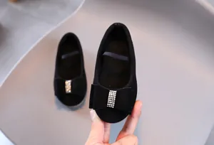 Détail de chaussures princesse en daim noir avec nœud en strass et bride élastique