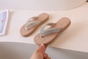 Close-up of beige flip-flops featuring sparkling rhinestone straps and woven texture soles