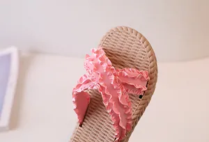 Close-up of pink ruffled criss-cross straps and woven texture sole on summer slippers