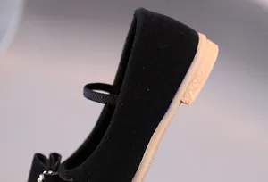 Détail de chaussures Mary Jane noires en daim pour fille avec décoration de nœud élégante