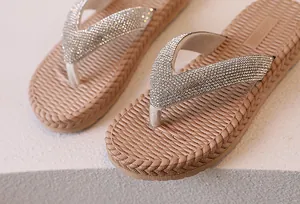 Macro view of apricot flip-flops featuring silver rhinestone straps and braided sole edges