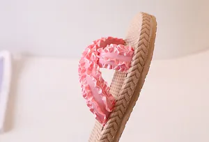 Detail of pink ruffled fabric straps and woven texture sole on casual beach slides