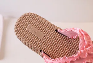 Detail of pink ruffled fabric slippers with woven texture sole and size 27-28 marking