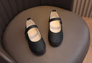 Gros plan de ballerines Mary Jane pailletées noires avec bordure ondulée pour fille