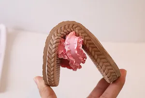 Pink ribbon slide slipper featuring a flexible non-slip brown sole being bent 180 degrees