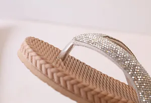 Macro shot of silver rhinestone straps and woven straw texture on flip flop sandals