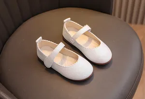 Détail de chaussures Mary Jane blanches scintillantes avec bords ondulés sur cuir