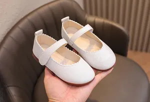 Détail de chaussures Mary Jane blanches pailletées avec bord festonné et velcro