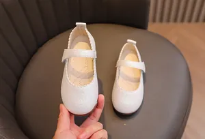 Détail de chaussures Mary Jane blanches à paillettes pour filles avec bord festonné et velcro