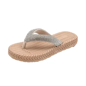 Detailed view of beige flip-flops with sparkling silver rhinestones and woven texture